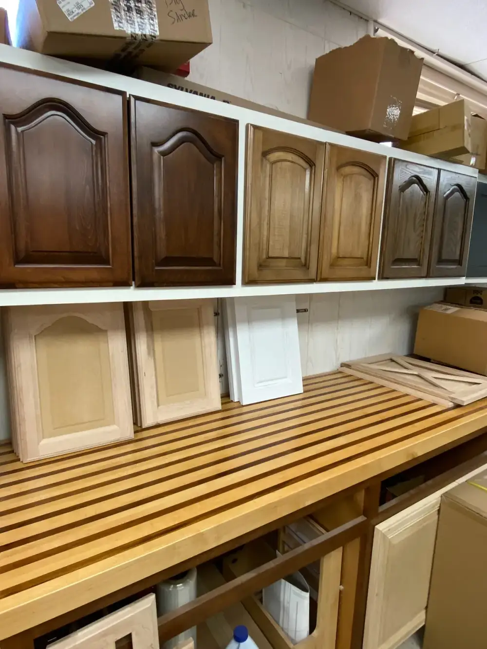 Stained and unfinished cabinet door samples displayed above the workbench at Trinity Doors